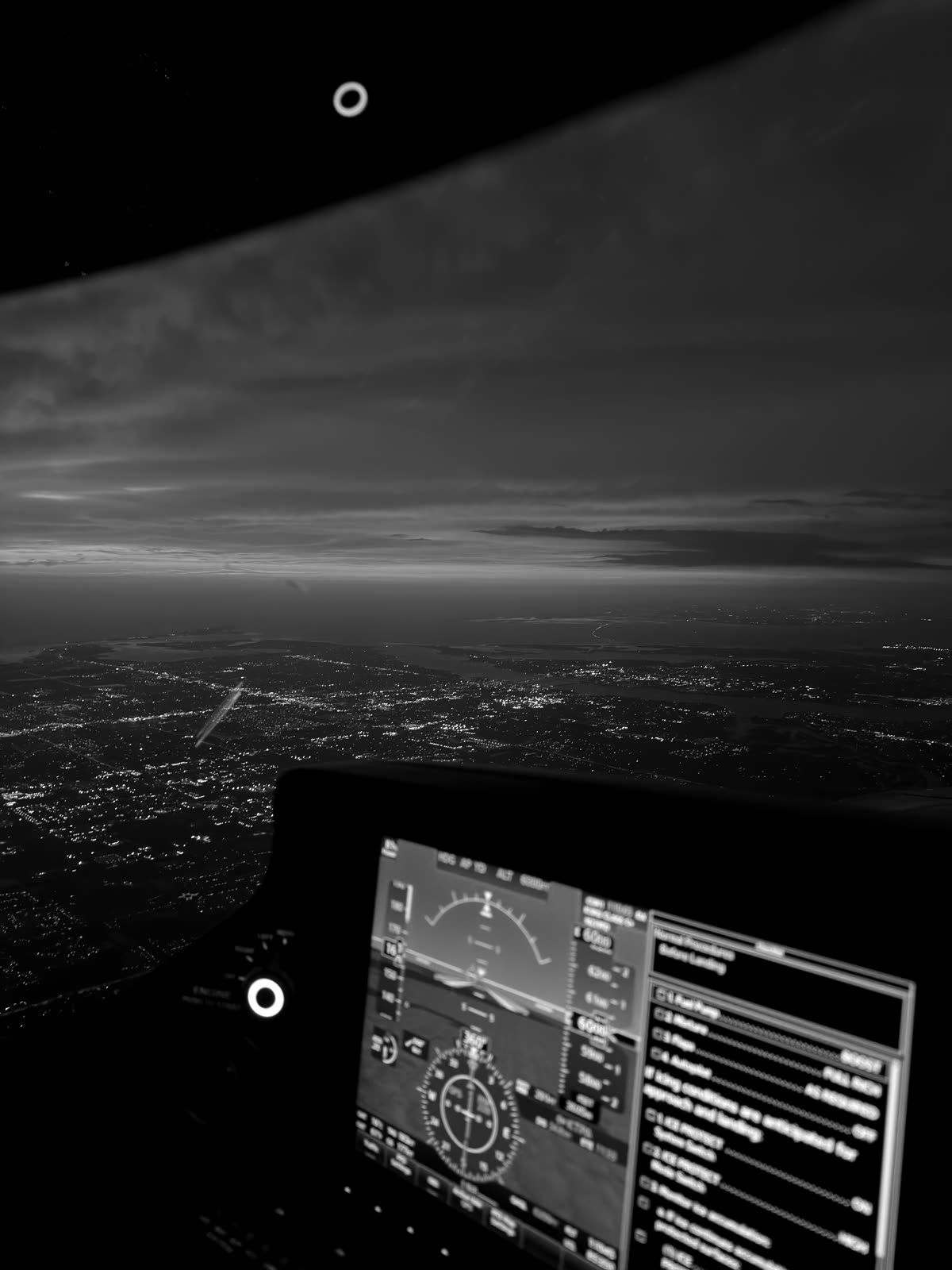 Last light on the horizon with city lights below, seen past the Garmin Perspective panel